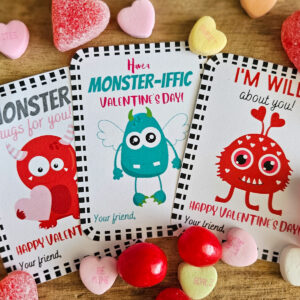 Three monster valentine cards surrounded by valentine candy.