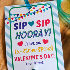 Colorful Valentine Card attached to a blue silly straw. The card has a blue striped background and flag banner on the top. The card reads, "sip, sip, hooray! Have an ex-straw special Valentine's Day!